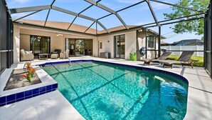 A swimming pool with a glass enclosure, a patio area with lounge chairs, and a view of the house. - Family Friendly 3BR Beach House with salt water heated pool (Englewood)
