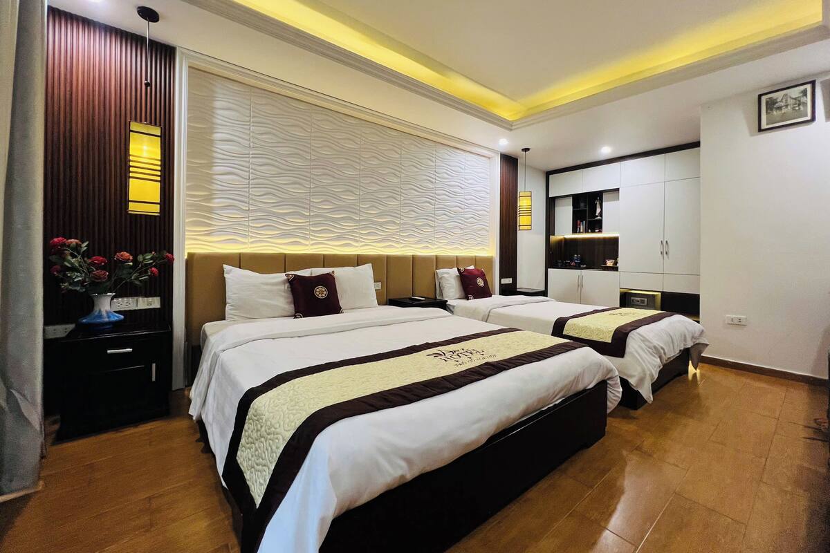 Una habitación de hotel con dos camas, un tocador y un armario.