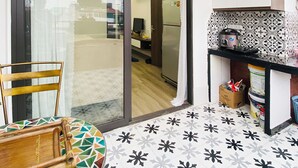 A modern kitchen with a refrigerator, a sink, and a countertop. There is a dining area with a chair and a table. The floor has a geometric tile pattern. - Art Hotel Ha Noi (Hanoi)