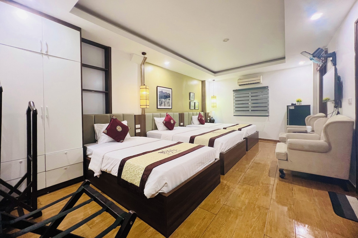 A hotel room with two beds, a wardrobe, a desk, a chair, and a television.