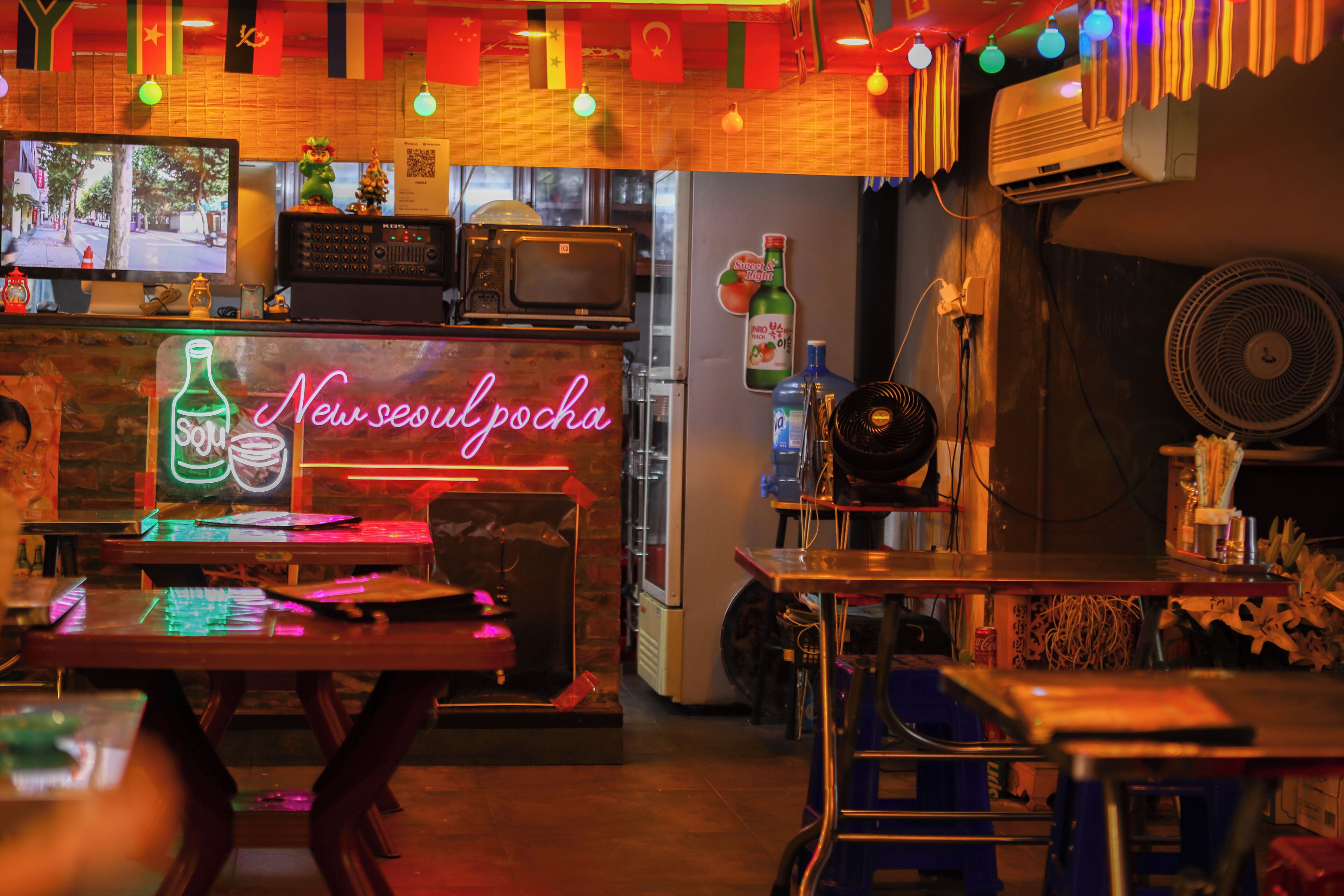 Eine Bar mit einer Neonreklame, einem Fernseher und verschiedenen Flaschen.