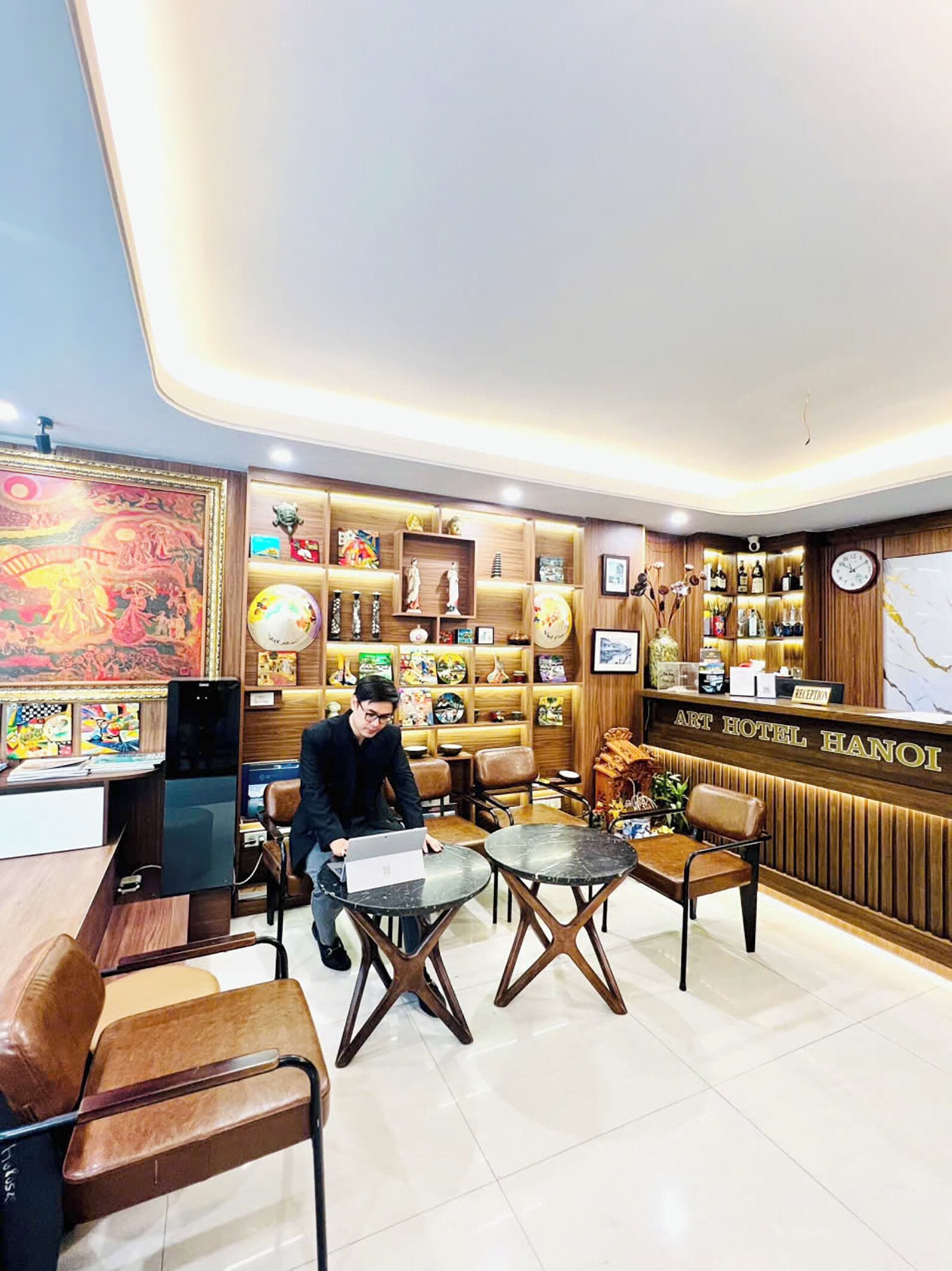 Un vestíbulo de hotel con una recepción, zona de estar y varios objetos decorativos.