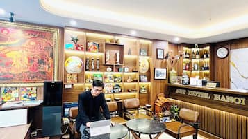 Un vestíbulo de hotel con una recepción, zona de estar y varios objetos decorativos.