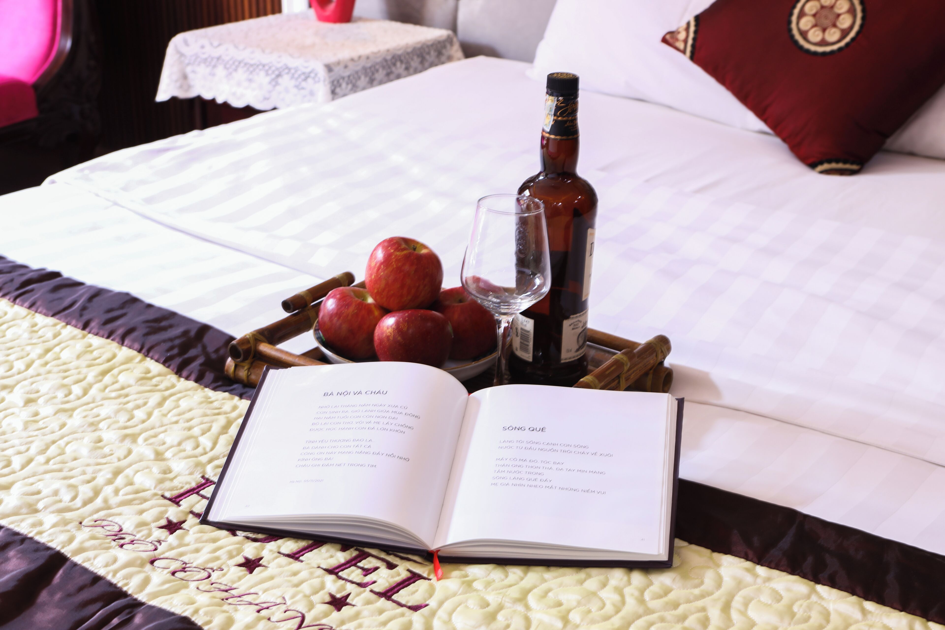 Een bed met een boek, een fles en appels.