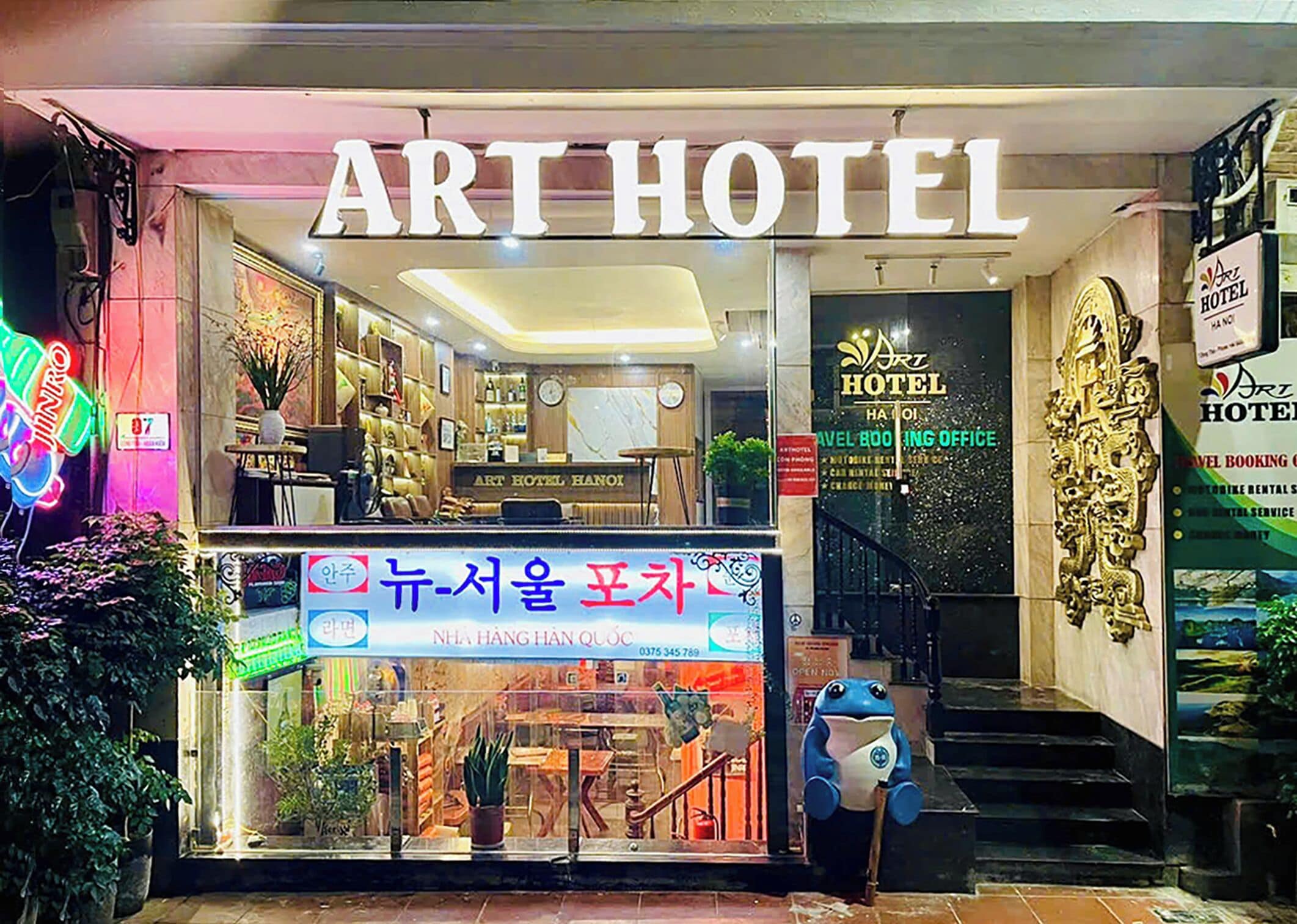 An Art Hotel with a travel booking office, a neon sign, and a statue.