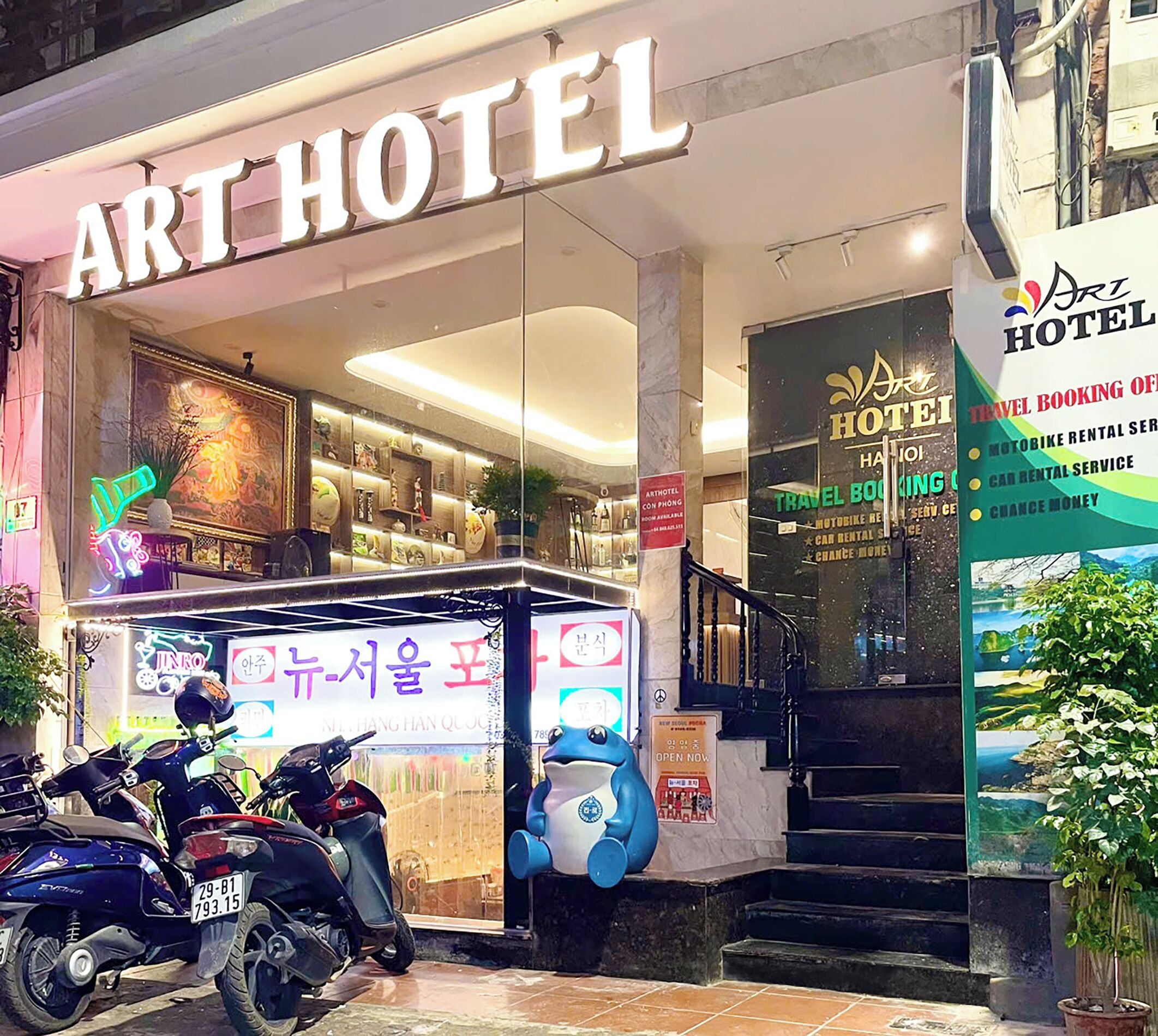 Um hotel com design artístico, um letreiro neon, aluguel de motocicletas e uma escadaria que leva à entrada.