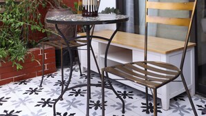 A small patio with a round table, two chairs, a vase of flowers, and a brick wall. - Art Hotel Ha Noi (Hanoi)