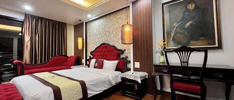 A hotel room with a large bed, a desk, a chair, and a painting on the wall.