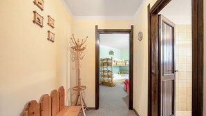 Un pasillo con un banco de madera, un perchero y una puerta que da a un dormitorio con cama y cómoda.
