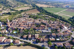 Une vue aérienne d’une ville où l’on aperçoit un ensemble dense de bâtiments, de routes et de champs verdoyants.
