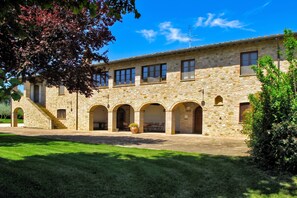 A stone building with multiple arched doorways and a staircase leading to an upper level.