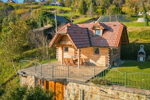 Una cabaña de madera con techo rojo, paredes de piedra, un balcón y una escalera de piedra.