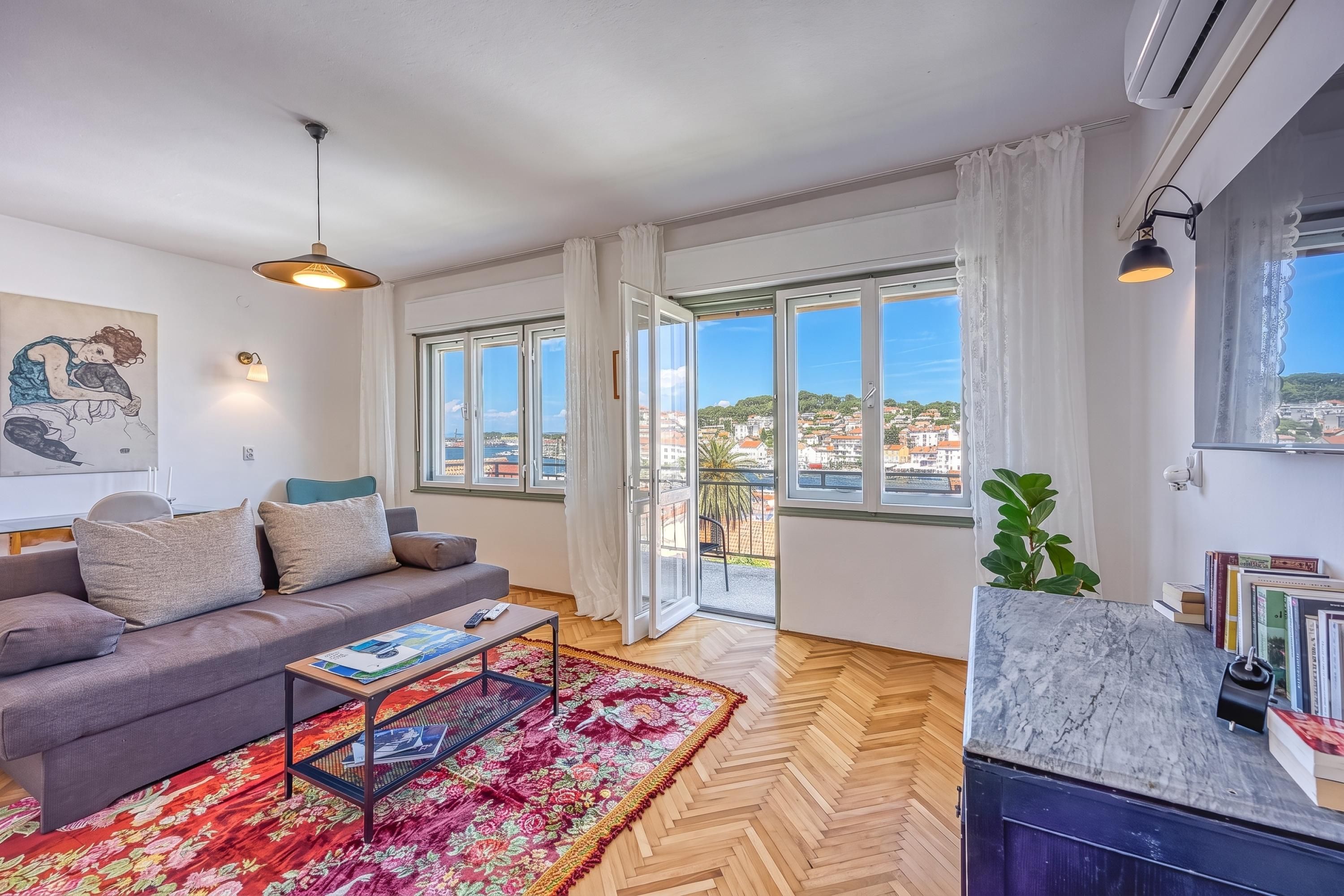 A modern living room with a sofa, coffee table, and a view of the city through large windows.
