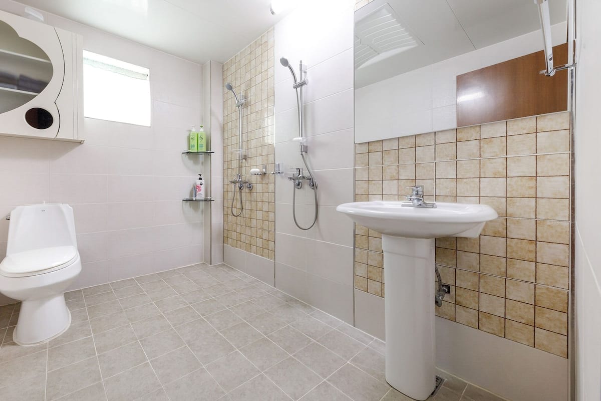 A bathroom with a toilet, a sink, and a shower area.