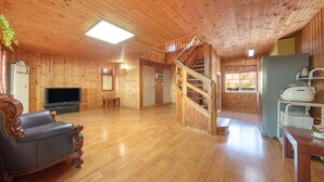 Un interior de madera con una escalera, un televisor, un sofá y una zona de cocina.