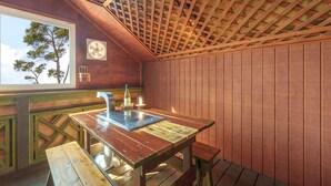 Un interior de madera con una mesa, un banco y un ventanal con vistas a árboles.