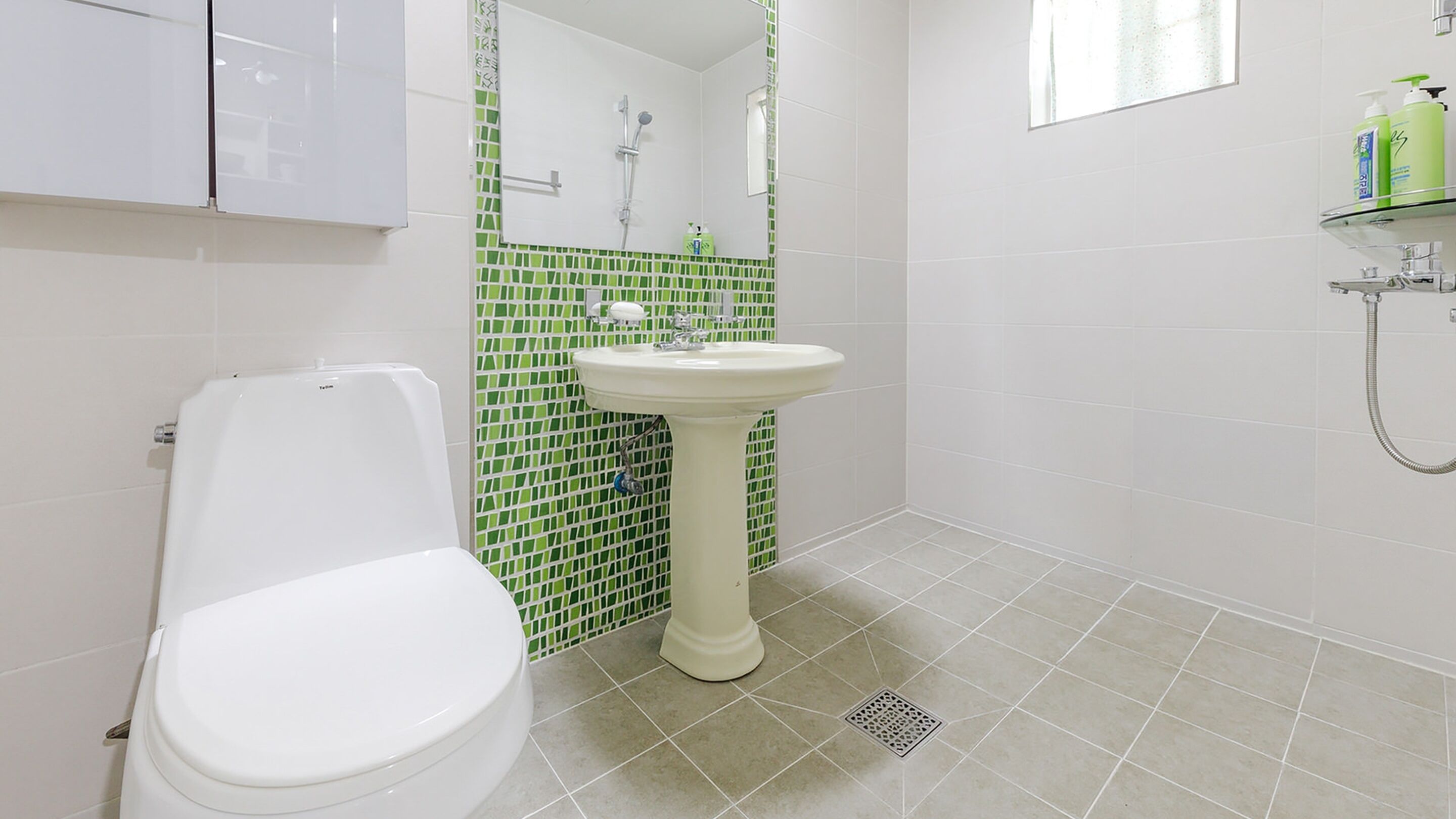 A bathroom with a toilet, a pedestal sink, and a shower.