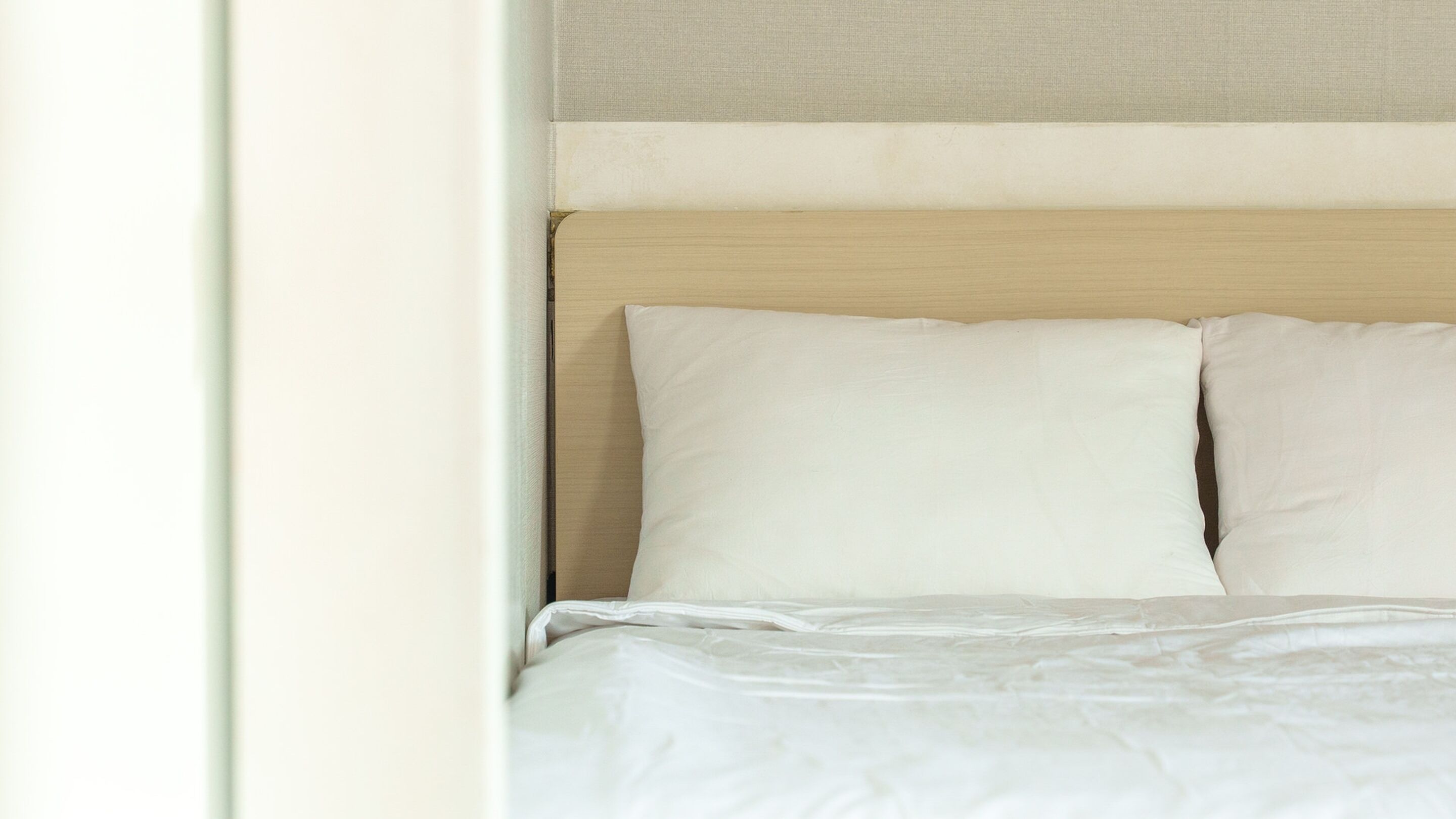 A bed with white bedding and a wooden headboard.