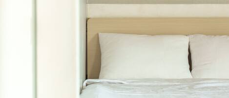 A bed with white bedding and a wooden headboard.