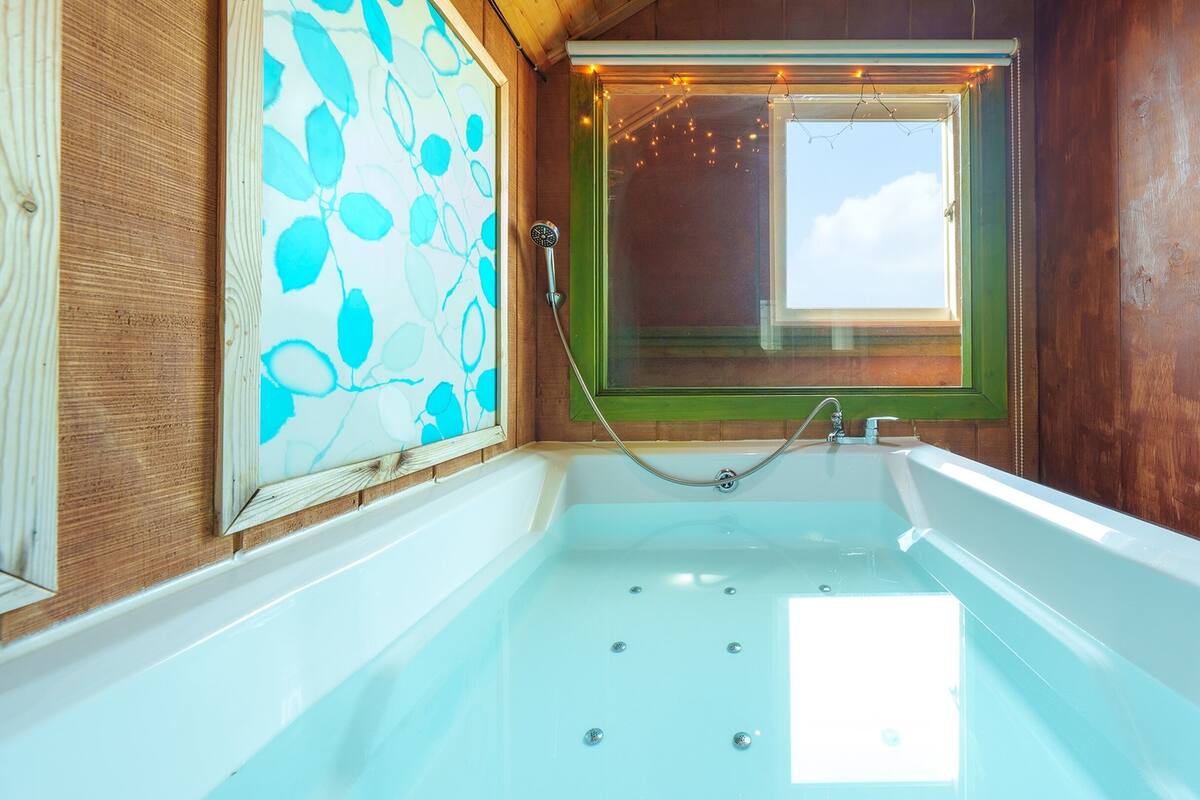 A bathroom with a bathtub, a window with a view, and a shower area.