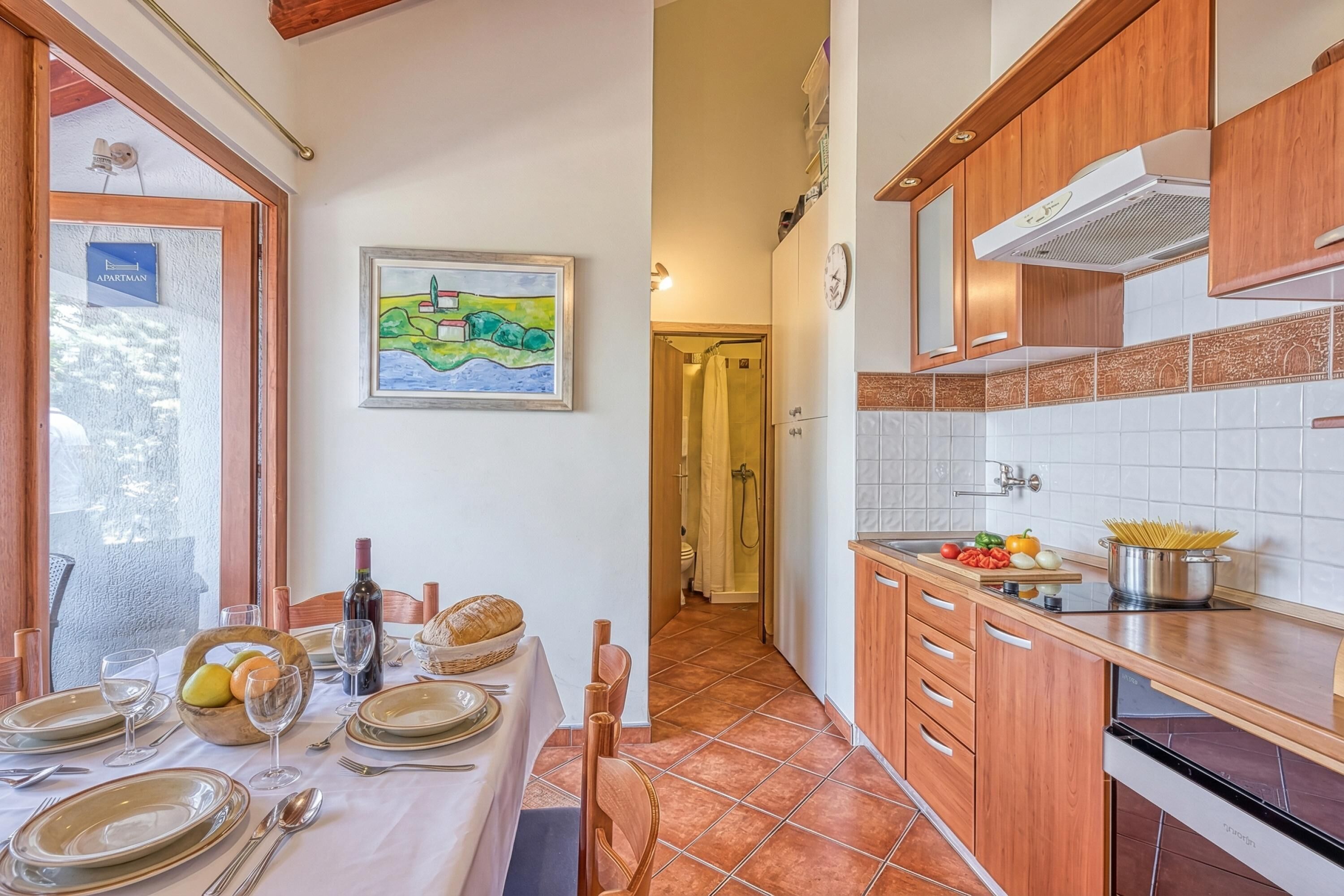 A kitchen with wooden cabinets, a tiled backsplash, and a dining area with a table set for two.