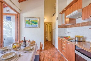 A kitchen with wooden cabinets, a tiled backsplash, and a dining area with a table set for two.