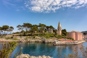 A coastal town with a prominent church tower, a waterfront area with outdoor seating, and a rocky shoreline.