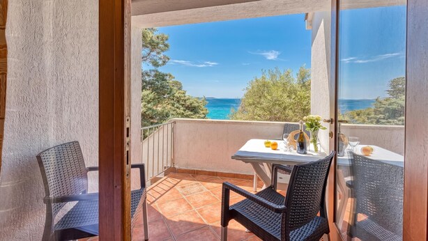 En balkon med et bord dækket til to, der giver udsigt over et smukt havlandskab.