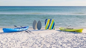 A beach with kayaks and paddleboards lined up on the sand. - Steps from Beach! First Level Condo, Walk to Pier (Saint Simons Island)