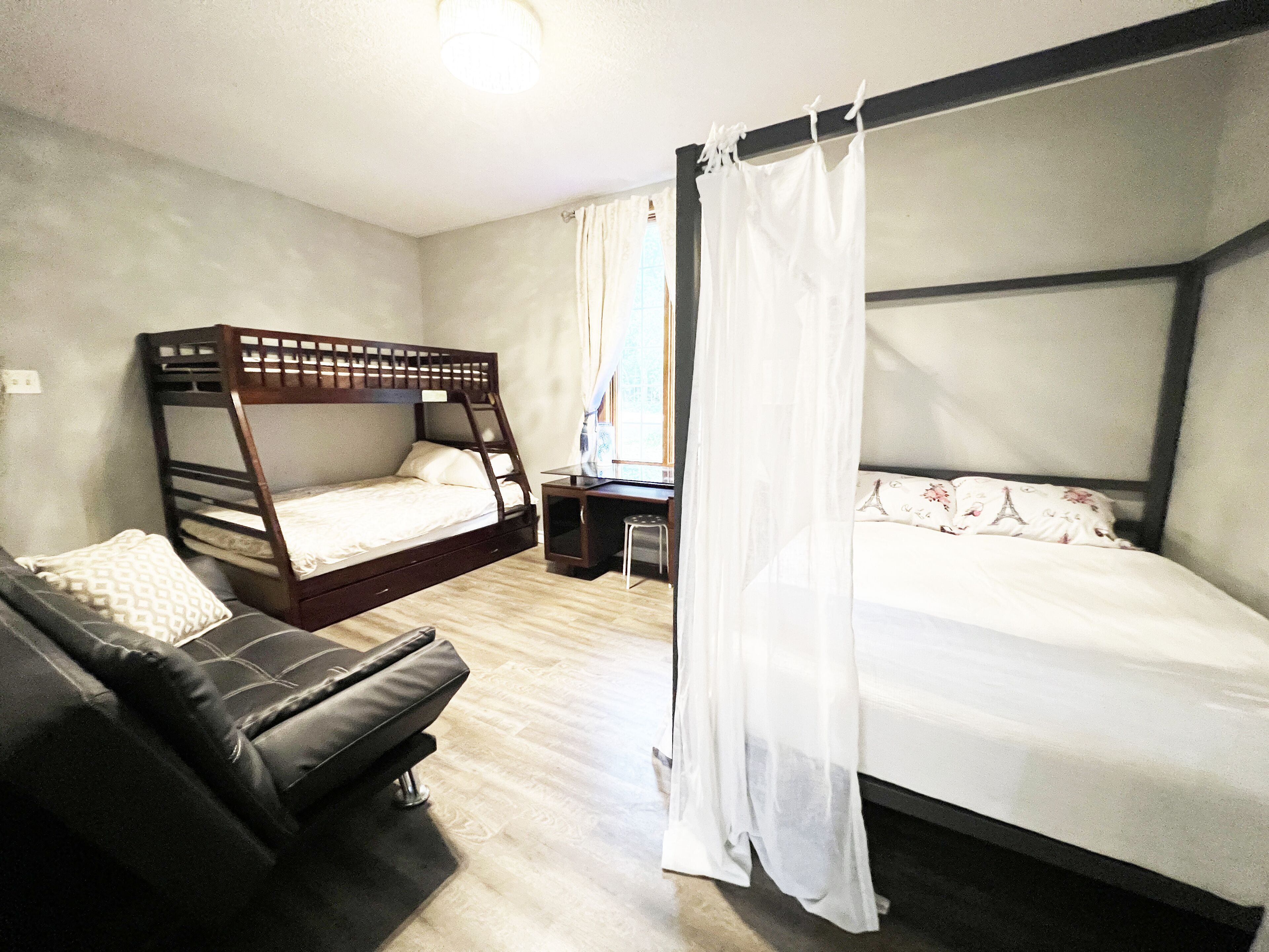 A room with a bunk bed, a single bed, a desk, and a chair.