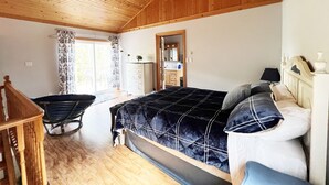 Un dormitorio con cama, cómoda, silla y ventana con cortinas.