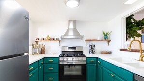 A kitchen with teal cabinets, a stainless steel refrigerator, a gas stove, and a built-in oven.
