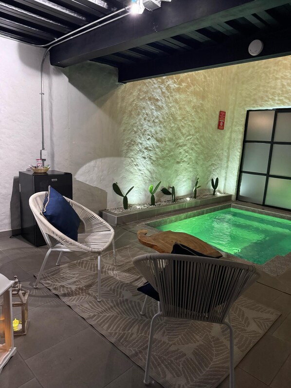 A modern indoor pool area with a green pool, lounge chairs, and a decorative wall.