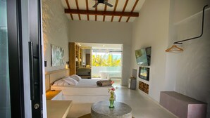 A modern hotel room with a bed, a round coffee table with a vase, a ceiling fan, and a view of the outdoors. - ECOPARADISE (Pereira)