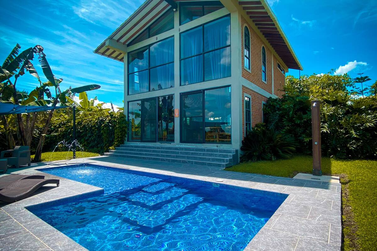 A modern house with a swimming pool, large windows, and a well-maintained garden.