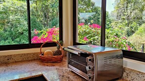 Un four à pain grillé posé sur un plan de travail dans la cuisine, avec vue sur un jardin par la fenêtre.