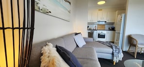 Cozy living area with a sofa, wicker chair, and kitchenette.