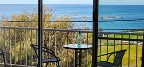 A balcony with a table, two chairs, and a bottle of wine.