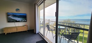 Enjoy the ocean view from this balcony with a table, chairs, and a TV displaying the sea.