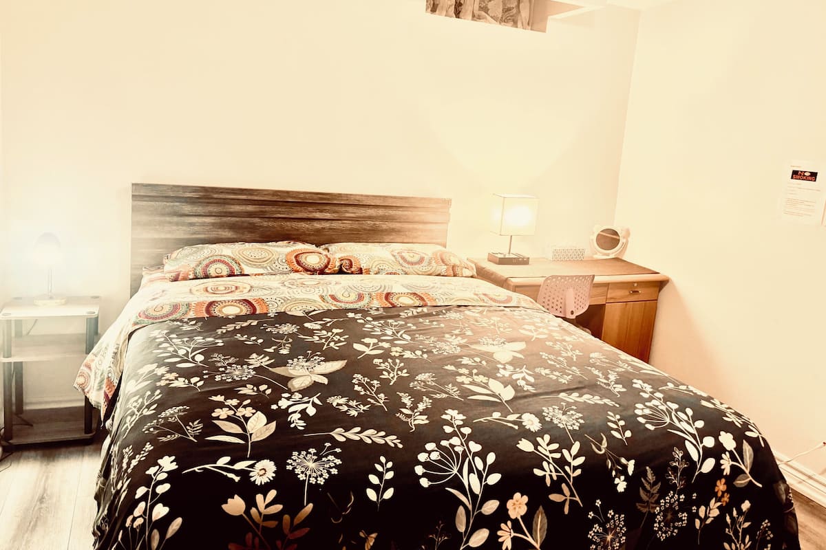 A bedroom with a bed, bedside tables, a desk, and a chair.