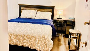 A bedroom with a bed, a nightstand, a desk, and a chair. - Cozy Home (Markham)