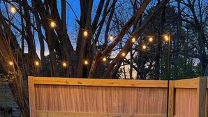 A wooden deck with a fire pit and Adirondack chairs.