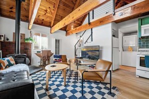 A living room with a fireplace, a television, and a kitchen area with a microwave.