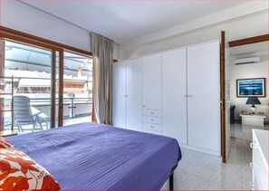Un dormitorio con cama, armario, escritorio y vistas al exterior.