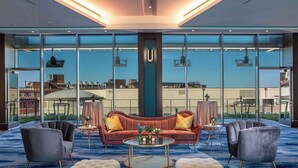 Eine moderne Hotelhalle mit einer großen Glaswand, einem roten Sofa, zwei Sesseln und einem runden Couchtisch.
