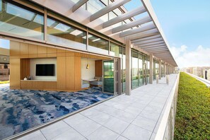 Een modern gebouw met een overdekt buitengebied, inclusief een zithoek, een flatscreen televisie en een kleine kitchenette.