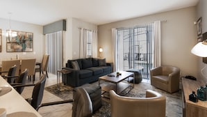 A modern living room with a sofa, armchairs, a coffee table, and a dining area with chairs and a table. - 8957sid-the Retreat At Championsgate 4 Bedroom Townhouse by RedAwning (Davenport)