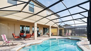 Ein Schwimmbecken mit Liegestühlen und einer überdachten Terrasse.