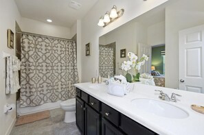 A bathroom with two sinks, a shower with patterned curtains, and a large mirror. - 1287yc - West Haven Gated Community 6 Bedroom Home by RedAwning (Davenport)