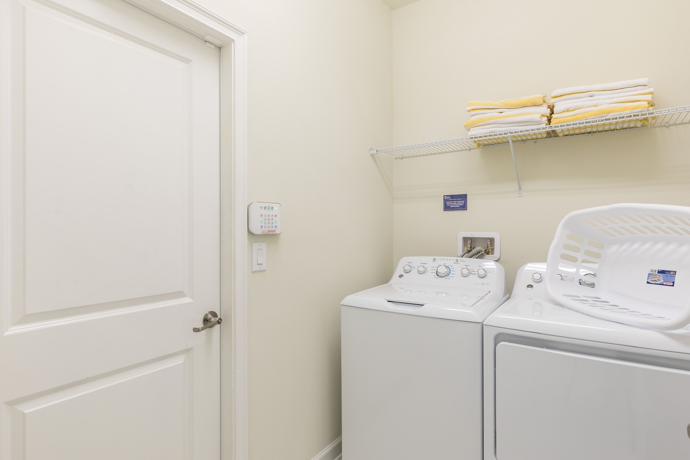 A laundry area with a washing machine, dryer, and a shelf with folded towels.